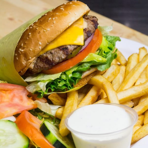 Cheeseburger with lettuce, tomato, and onion, served with fries, a side salad, and ranch dressing.